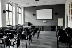 wnętrze sali multimedialnej, ekran na scianie i krzesła