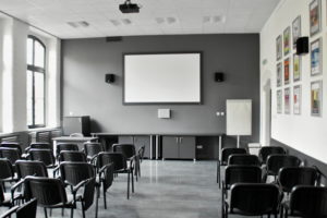 wnętrze sali multimedialnej, ekran na scianie i krzesła