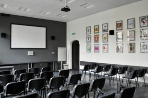 wnętrze sali multimedialnej, ekran na scianie i krzesła