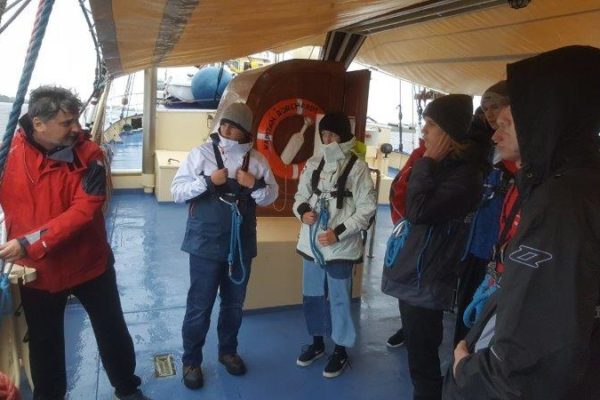 Oficer Marcin przeprowadza szkolenie na śródokręciu dla I wachty z prawidłowego wpinania się pasami do elementów stałych