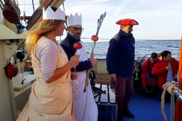 Na śródokręciu na pierwszym planie jest Neptun wraz z Prozerpiną oraz kapitan żaglowca. Obok nich widać klęczących uczniów uczestników Chrztu Morskiego .W tle widać morze aż po horyzont.