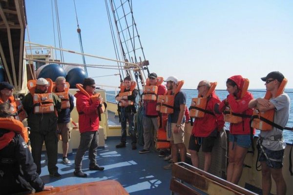 Załoga stała żaglowca oraz kadra SKEM w pomarańczowych kapokach podczas szkolenia opuszczenia statku