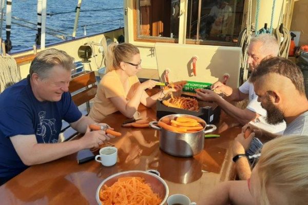 5-osobowa wachta kambuzowa przy stole obiera marchewkę do surówki