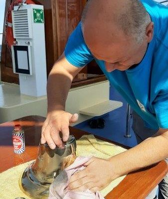 Darek czyści, poleruje dzwon żaglowca