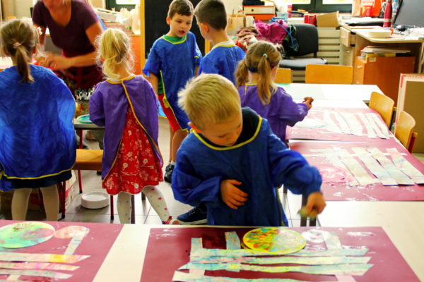 Przedszkolaki na zajęciach plastycznych, na pierwszym planie chłopiec pochylony nad pracą plastyczną