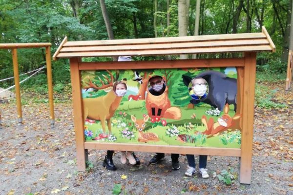 Plansza edukacyjna na ścieżce przyrodniczej Syrenich Stawów - portret jelenia, lisa i dzika z wyciętymi otworami na głowy