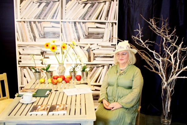 Danuta Romana Słowik siedząca na krześle przy stole podczas wieczoru literackiego