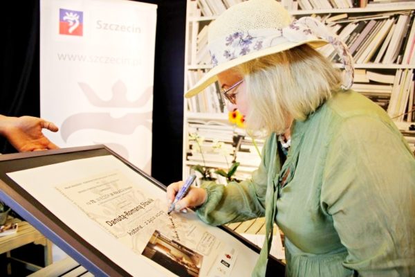 Autorka podpisuje plakat promujący spotkanie literackie