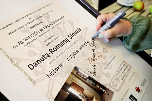 Autorka podpisuje plakat promujący spotkanie literackie