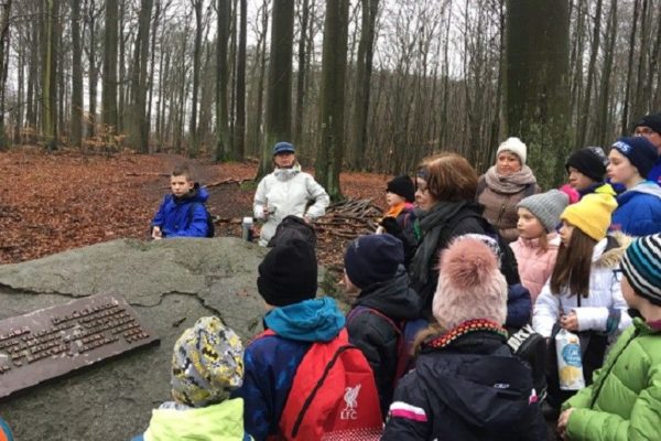 Grupa młodzieży z opiekunami przy głazie