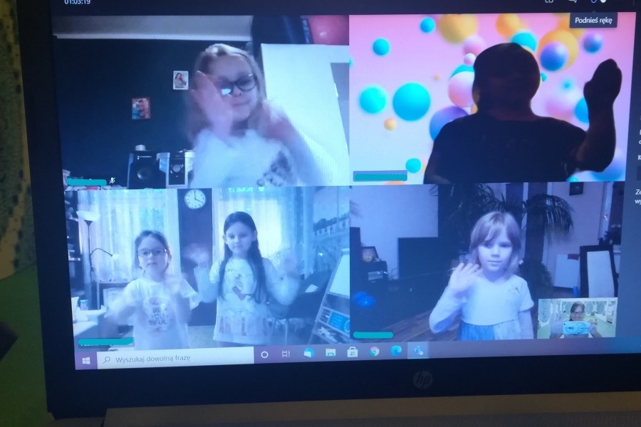 Na zdjęciu monitora komputera w podzielonych okienkach sześć dziewcząt stoi w pozie tanecznej zjedna ręka wyprostowana do boku, a druga ugiętą w łokciu.