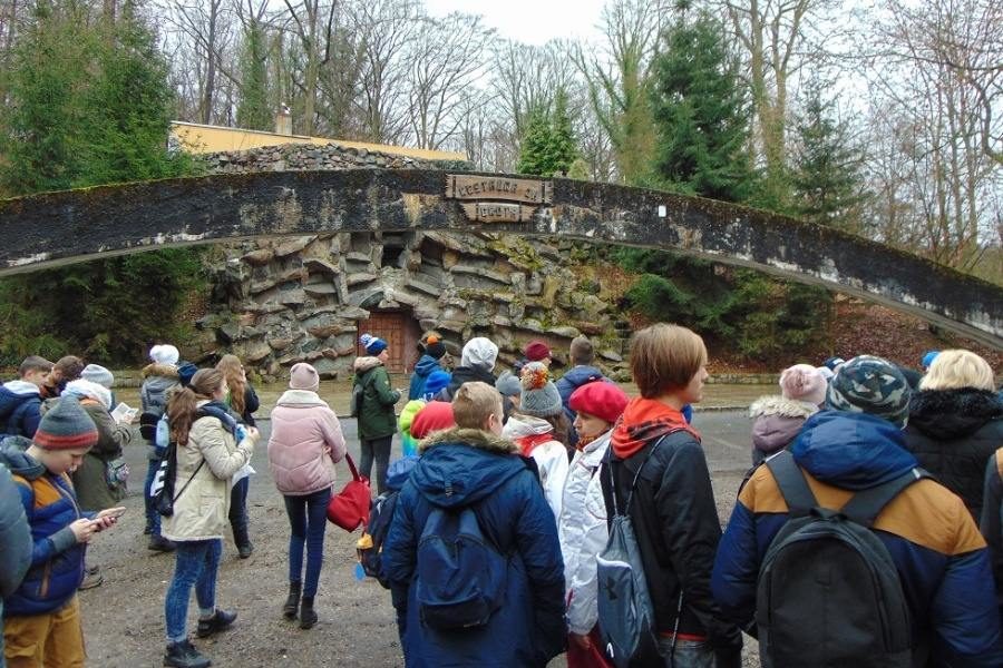 dzieci przed sztuczną grotą w Parku Leśnym Zdroje, w tle betonowy łuk z napisem Grota