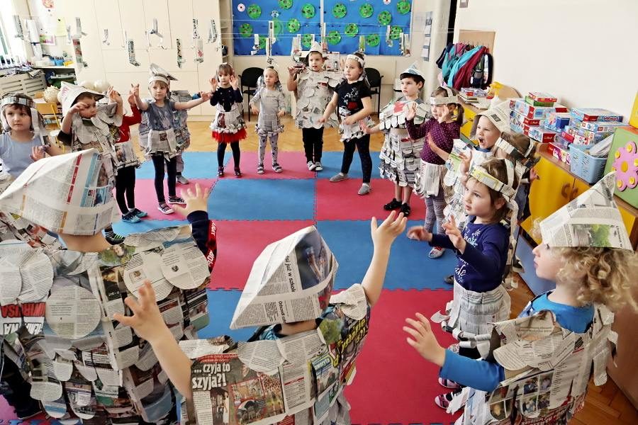 przedszkolaki w gazetowych strojach stoją w kregu