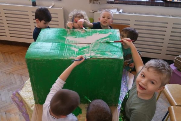 grupa przedszkolaków maluje na zieolono karton