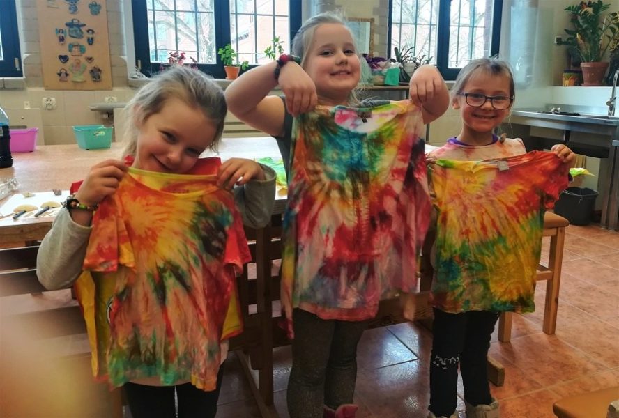 trzy dziewczynki stoją obok siebie trzymając zabarwione koszulki