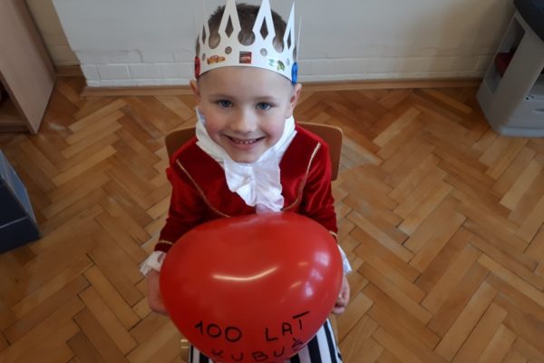 chłopiec w stroju króla trzymający serce balonowe