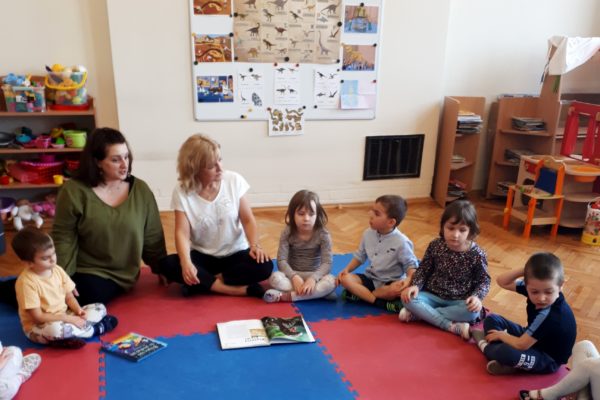 grupa przedszkolaków z nauczucielkami prezentującymi książki o dinozaurach