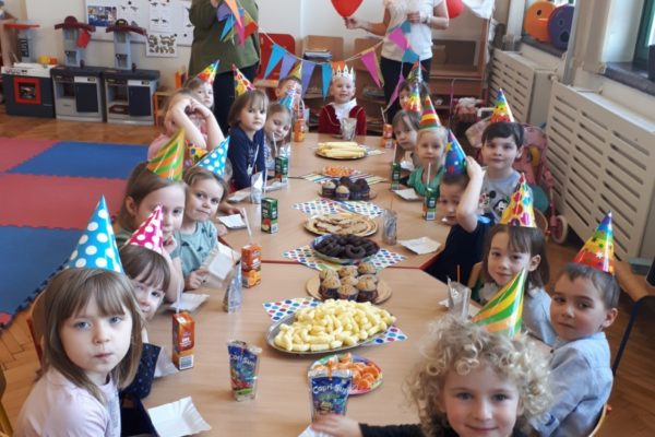 grupa przedszkolaków siedząca prz stole ze słodkościami