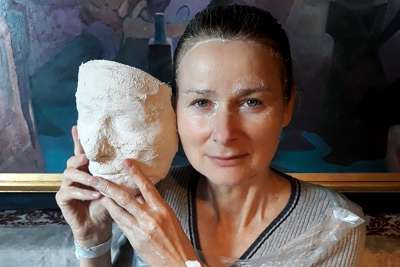 kobieta trzymająca w dłoniach maskę - odlew gliniany swojej twarzy