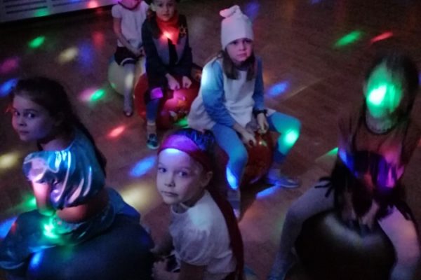 grupa dzieci w strojach karnawałowych w świetle lampek dyskotekowych