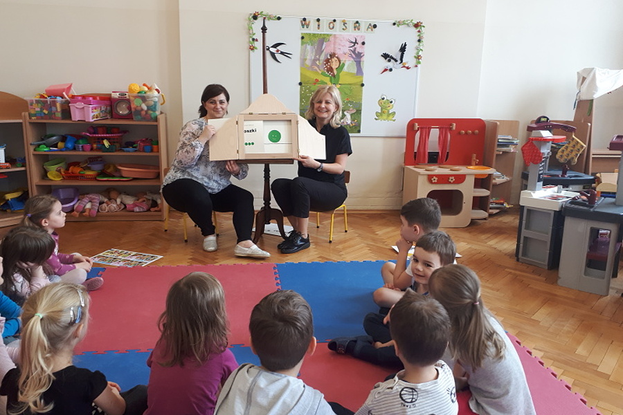 grupa przedszkolaków wraz znauczycielkami które prezentją dzieciom teatrzyk