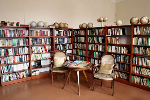 wnętrze biblioteki dwa fotele okrągły stolik w tle regały z książkami