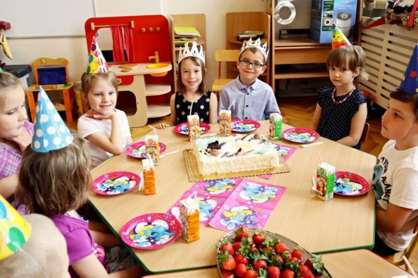 dzieci siedzące przy stole ze smakołykami