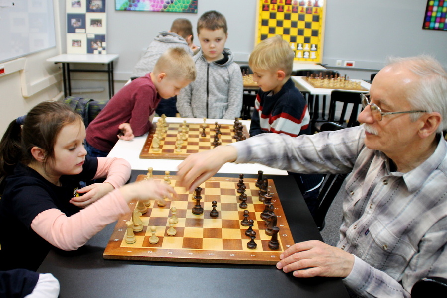 nauczyciel z dziećmi nad partią szachów