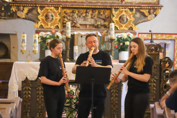 wnętrze kościoła i trzy osoby grafjące na instrumentach