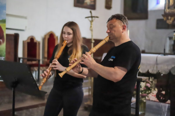 dwie osoby grające na fletach w kościele
