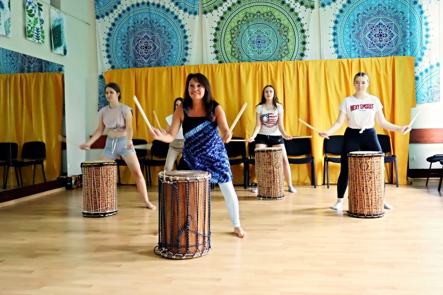 dziewcząt z nauczycielką grających na bębnach z kijkami