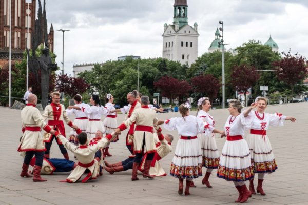 grupa ludzi w strojach ludowych w tle zamek