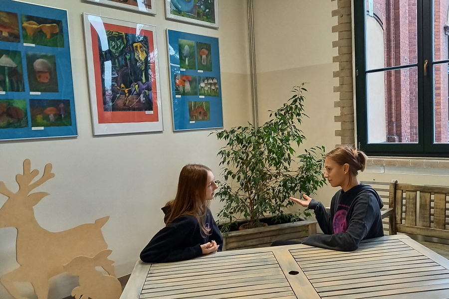 dwie dziewczynki siedzące przy stole podczas rozmowy