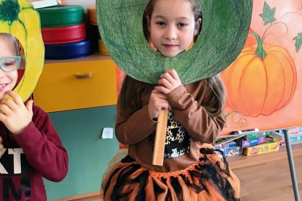 dziewczynka trzymająca na twarzy szablon dyni