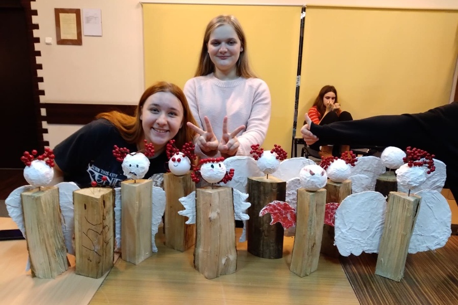 dwie uczestniczki pozujące do zdjęcia, na pierwszym planie wykonane figurki aniołów