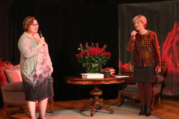 dwie kobiety z mikrofonami w dłoniach pomiędz nimi stolik z bukietem róż