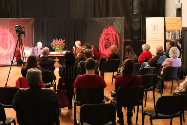 sala z publicznością kobieta i mężczyzna siedzą przy stoliku podczas rozmowy