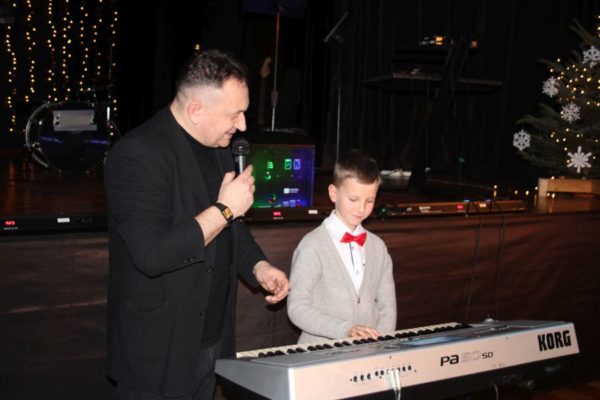 chłopiec grający na keyboardzie obok nauczyciel