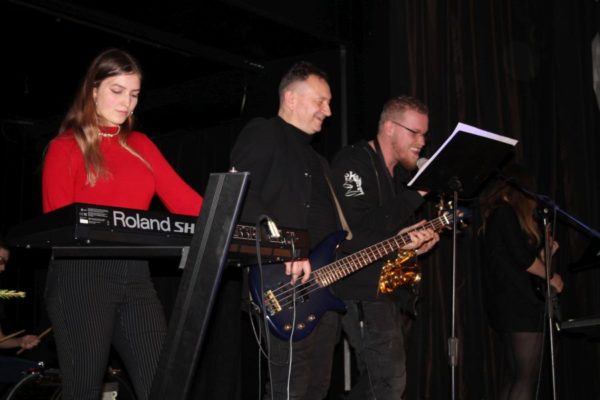 trzyosobowy zespoł muzyczny grający na scenie