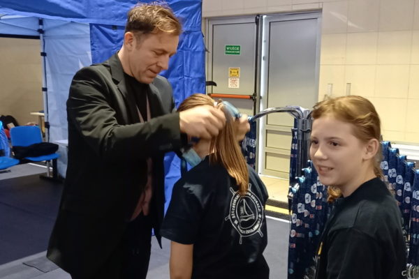 męzczyzna zakłąda medal dziewczynce na szyję