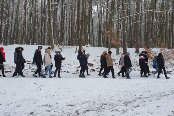 grupa młodzieży idąca przez zaśnieżowny las
