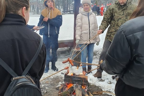 grupa ludzi piekąca kiełbaski przy ognisku