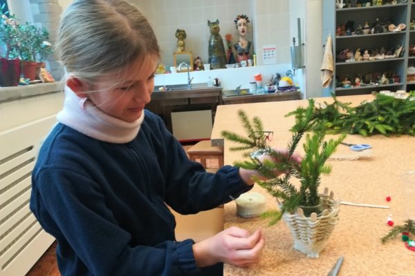 Dziewczynka Układająca świerk w koszyku.