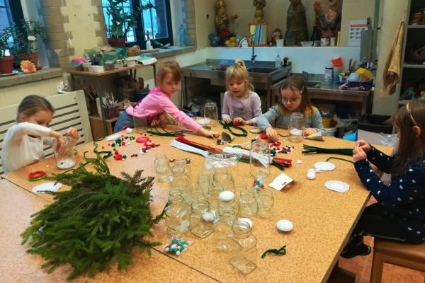 Grupa dziewcząt wykonująca ozdoby przy stole.