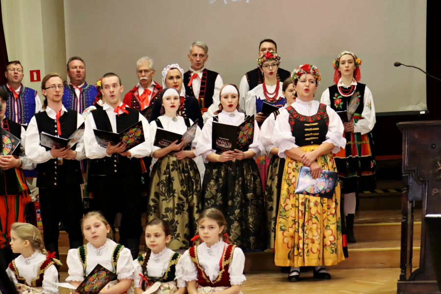 grupa tancerzy w strojach ludowych ze śpiewnikami w dłonaich