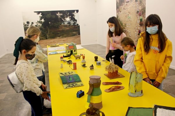 grupa dziewci oglądających wystawę na żółtym stole