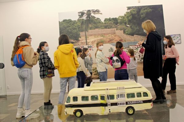 grupa dzieci oglądających wielką fotografię, na pierwszym planie model autokaru