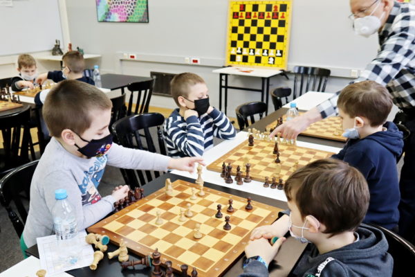 grupa dzieci siedzących nad szachami