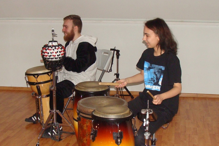 dwoje młodych ludzi grajacych na instrumentach - bębnach