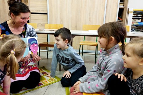 nauczycielka z książką i dwoje dzieci